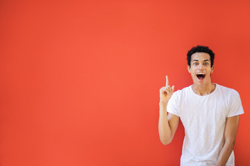 Excited young man pointing up his finger 