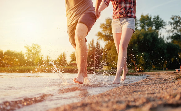 couple happy on the beach run motion legs sunset splashing water