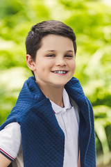smiling kid with jumper over shoulders looking at camera