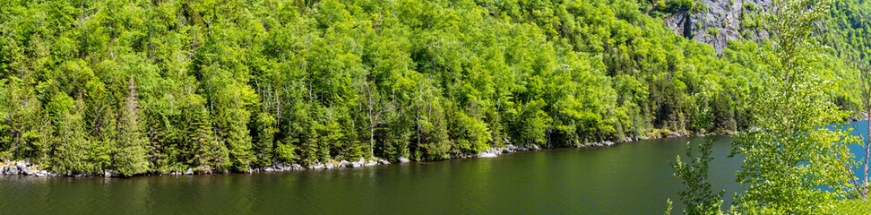 Panoramic view of a wooded cliff near a lake in Adirondacks Mountains