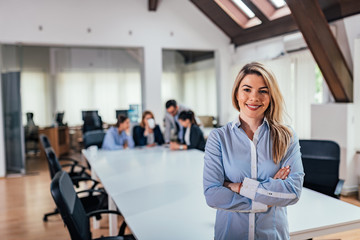 Business leader in office with team colleagues at background.