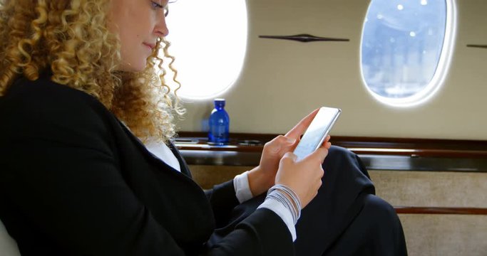 Businesswoman using mobile phone in private jet 4k
