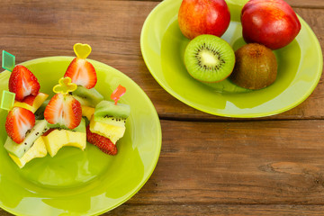 dish with canapés of peaches, kiwi and strawberries. next is a plate of kiwi and peaches. horizontal photo.