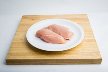 Raw chicken breast fillets on white dish