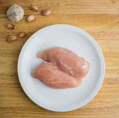 Raw chicken breast fillets on white dish