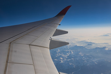 Obraz premium Snow mountain view in Europe with airplane wing through aircraft window