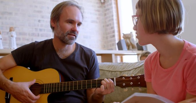 ather helping her daughter to play guitar in living room 4k