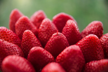 Many healthy red strawberries closeup on the background of the blurred background