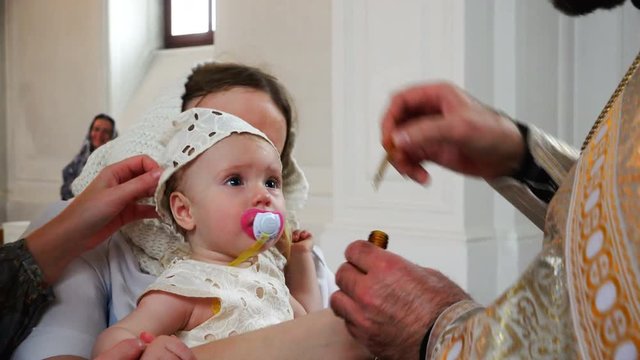 the holy father smears his forehead and handles to the infant with church oil.