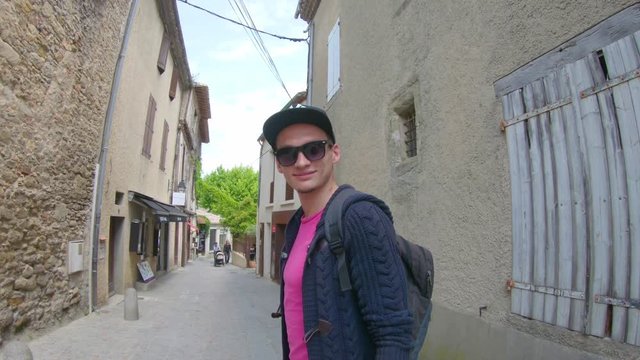 A young guy in a cap walking along the ancient streets of Carcassonne in France