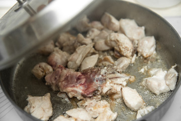 Meat in a frying pan with a lid slightly open