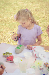 child painting stones outdoors