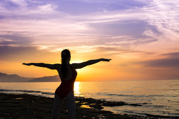 Fototapeta premium young girl practicing yoga on the beach during the sunset.
