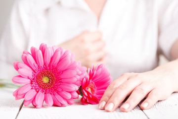Obraz na płótnie Canvas Pink flower gerbera in female hands, close up view female care concept
