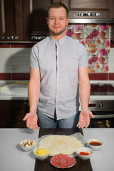 a man shows the ingredients of pizza