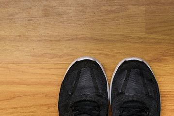 A pair of black sneakers isolated on a laminated wooden floor