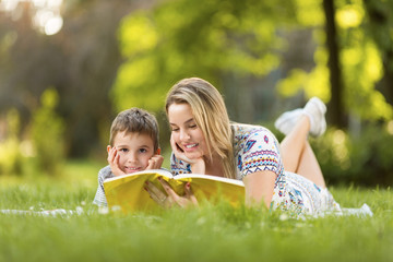 Mother and son reading a book in park