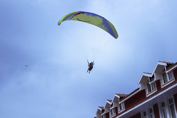 Fototapeta na wymiar Skydiver against the blue sky and the roof of the house