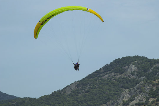 A man in a parachute is flying over the mountains. Parasailing.