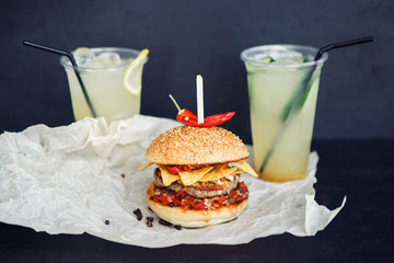Two beverages and one burger on the black background