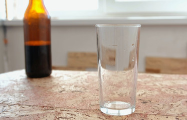 Dark beer is poured from a bottle into a glass.