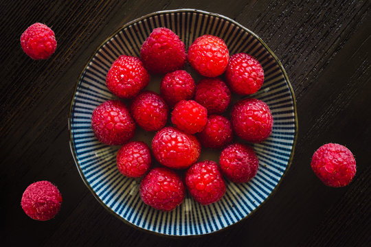 Fresh Raspberries in Bowl and on Wood Table