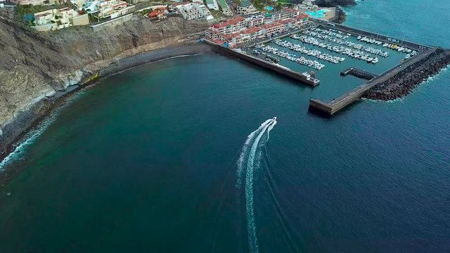 View from the height of the town near Los Gigantes on the Atlantic coast. Boat returns to the port. Tenerife, Canary Islands, Spain