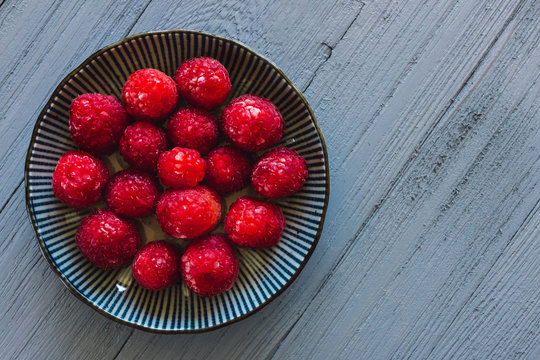 Red Raspberries on Blue Table with Space for Copy