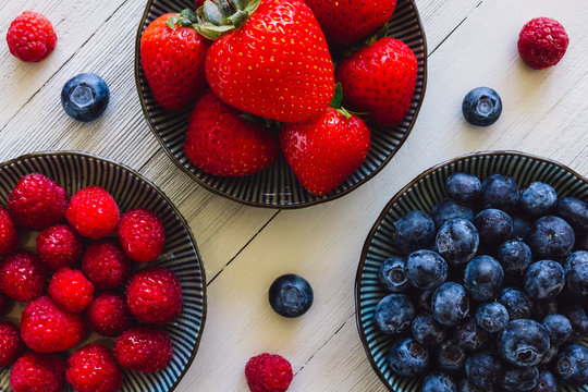 Strawberries, Blueberries and Raspberries Arranged on White Table