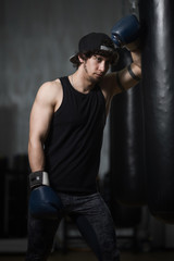 Young boxer posing next to punching bag