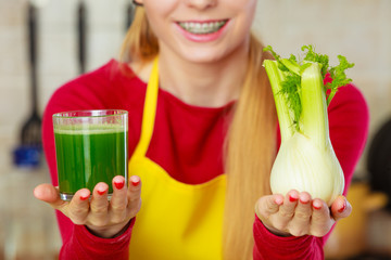 Woman in kitchen holding vegetable fennel smoothie juice