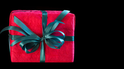 Beautiful red paper gift box with ribbon bow from above isolated on black.