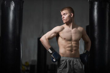 Fototapeta na wymiar Young boxer posing next to punching bag