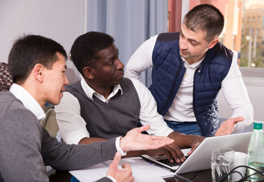 Three seriouse men are working with project on laptop together