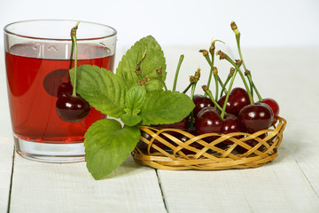 Cherry juice and fresh cherries on a wooden background. Fresh cherry juice in a glass. Fresh cherry on a wooden table.
