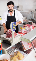 Man butcher is weighing meat in the market.