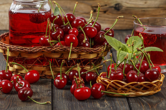 Cherry juice and fresh cherries on a wooden background. Fresh cherry juice in a glass. Fresh cherry on a wooden table.
