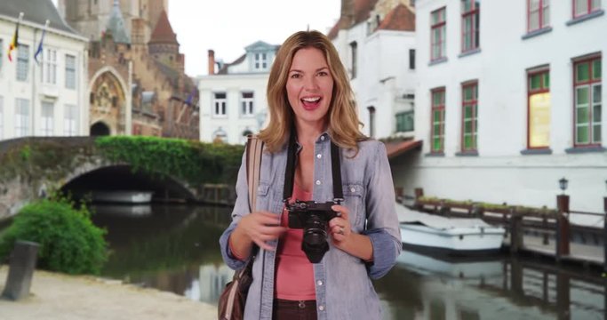 Travel photographer taking pictures in Bruges, Portrait of woman tourist with her camera talking outside, 4k