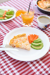 A simple breakfast of omelet, pieces of avocado and carrots, a cup of coffee and a glass of fresh orange juice during a summer holiday on a yacht.