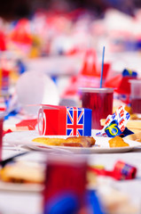 Children sit at long tables with red, white and blue party accessories at a Royal event street party