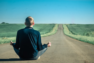 Silence, Lonely man meditating on a deserted road at sunset