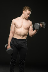 Fototapeta na wymiar young bodybuilder raises dumbbells on black background