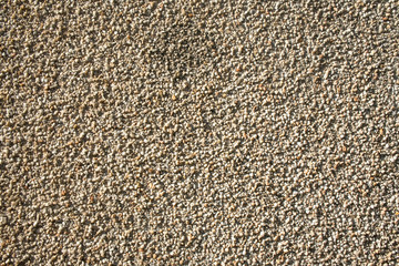 Fragment of an outdoor coating made of grey scabrous sand, closeup. Abstract grainy textured background.