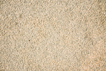 Fragment of a beige granite facing slab. Untreated scabrous stone surface of natural beige granite.