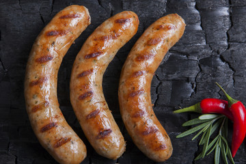 Grilled chicken sausages on a black background of charcoal. Barbecue grill