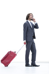 businessman with Luggage talking on a cell phone.