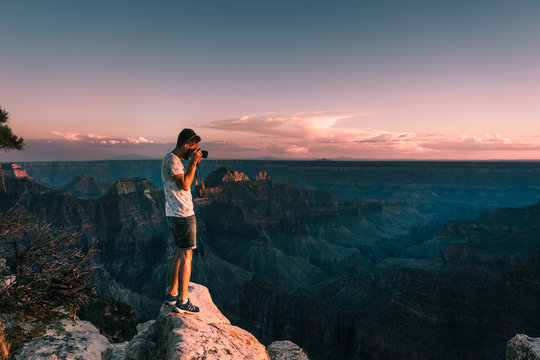young man takes picture of Magnificent Grand Canyon, Arizona, USA during sunset