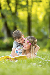 Mother and son in park outdoors on a blanket reading a book