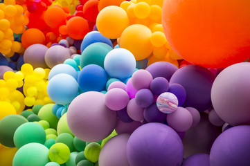 Fototapeta na wymiar Bright abstract background of jumble of rainbow colored balloons celebrating gay pride