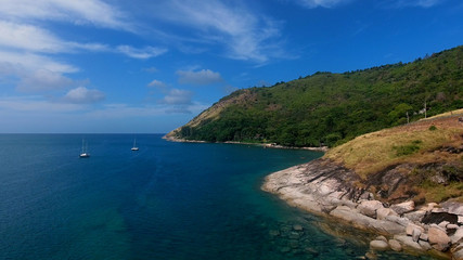 Copter aerial view of yacht moored in a bay near beach, where people are swimming and having sunbath